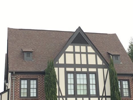 A brick and white house with a brown roof