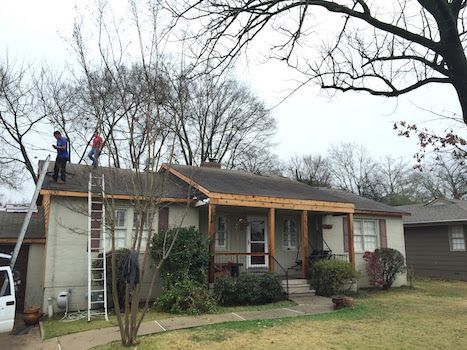 Two men are working on the roof of a house.