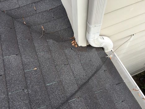 A close up of a gutter on a roof next to a house.