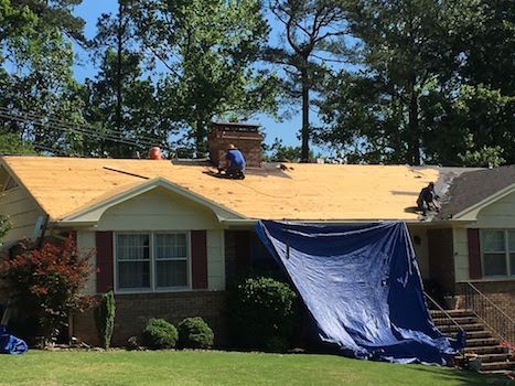 Two men are working on the roof of a house.
