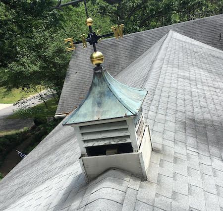 A weather vane is sitting on top of a roof.