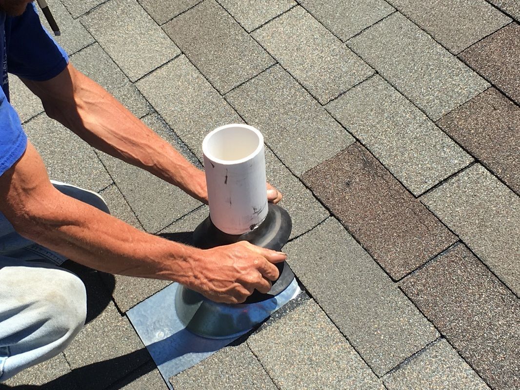 A man is installing a pipe on a brick roof.