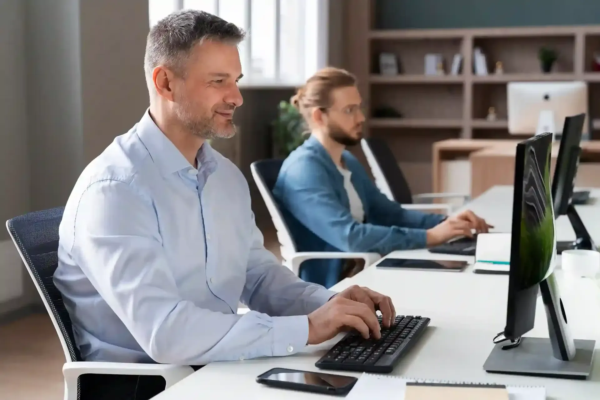 Two people working at computers in an office for IT Support Services Connecticut.