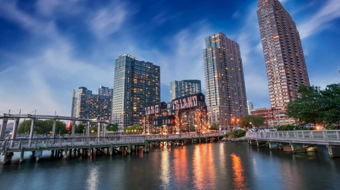 A city skyline with a pier in the foreground and a body of water in the background.