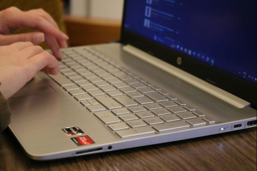 A person is typing on a silver hp laptop