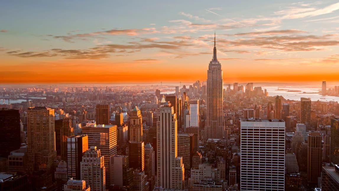 An aerial view of a city skyline at sunset with the empire state building in the foreground.