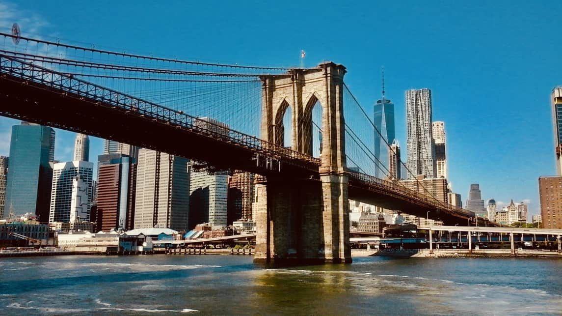 A bridge over a body of water with a city skyline in the background.