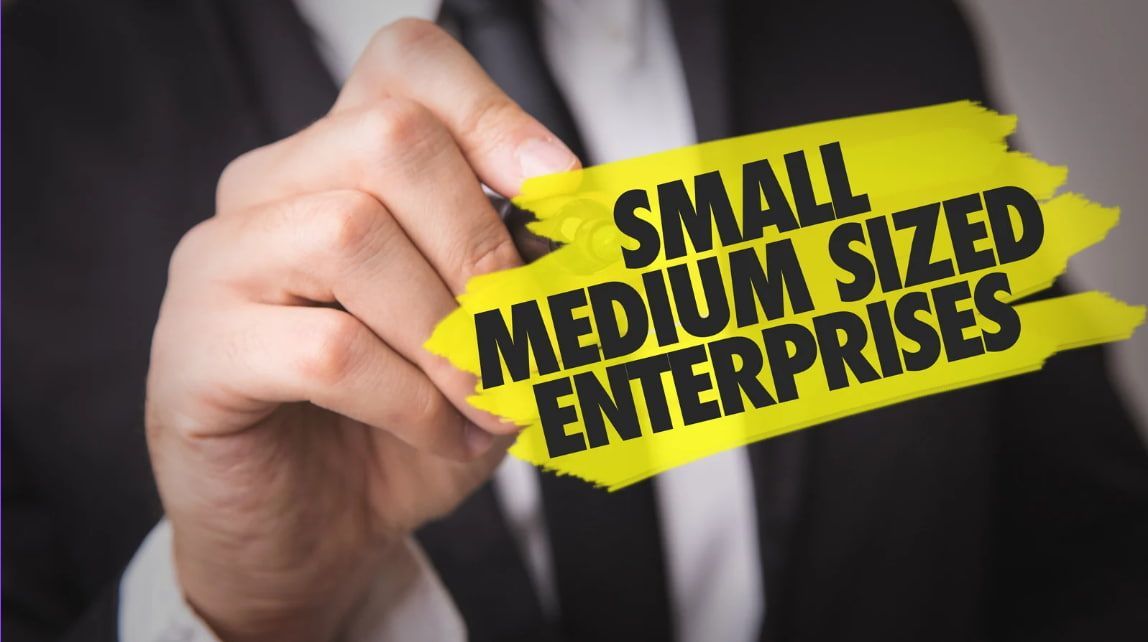 A man in a suit is writing small medium sized enterprises with a marker.