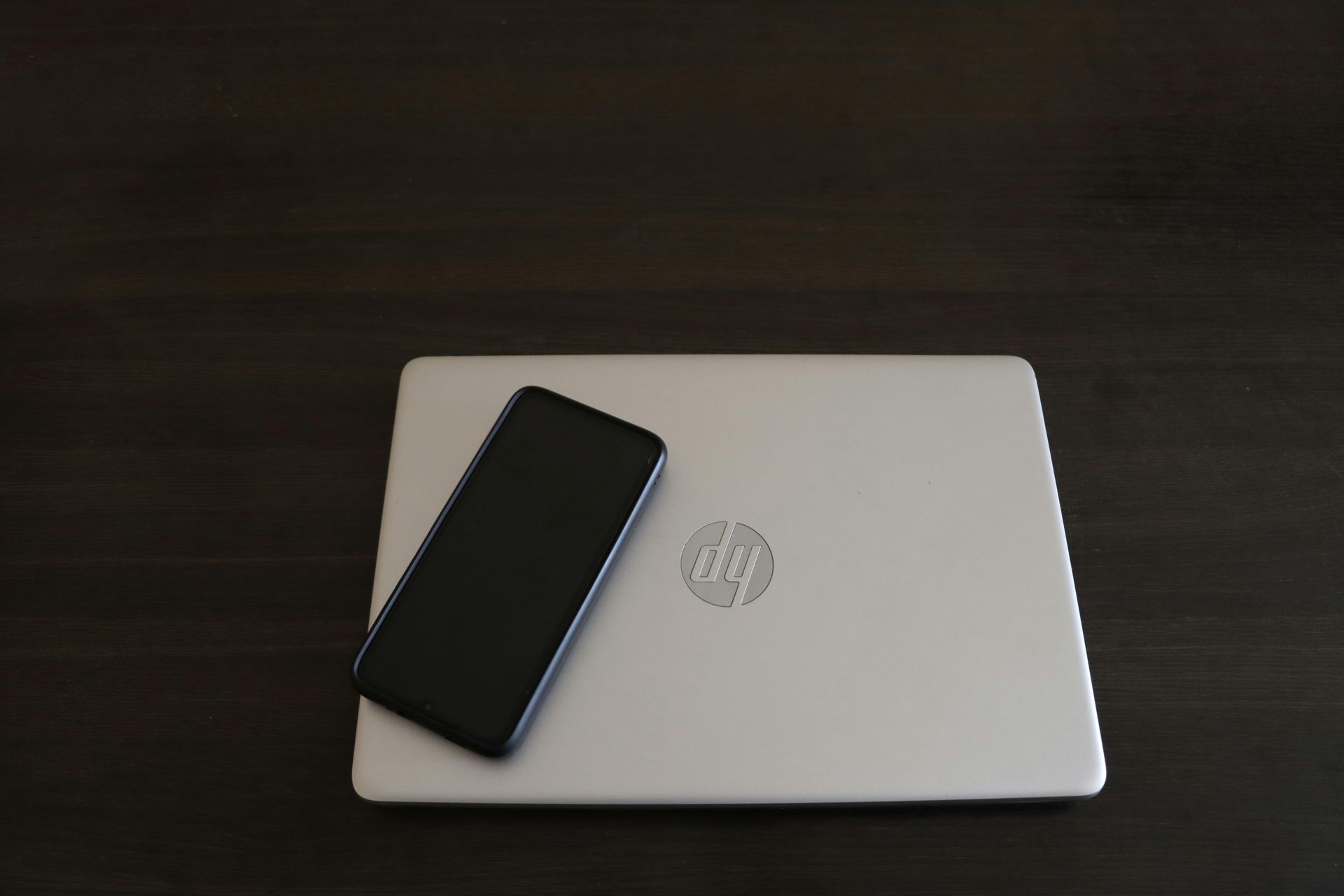An hp laptop with a cell phone on top of it