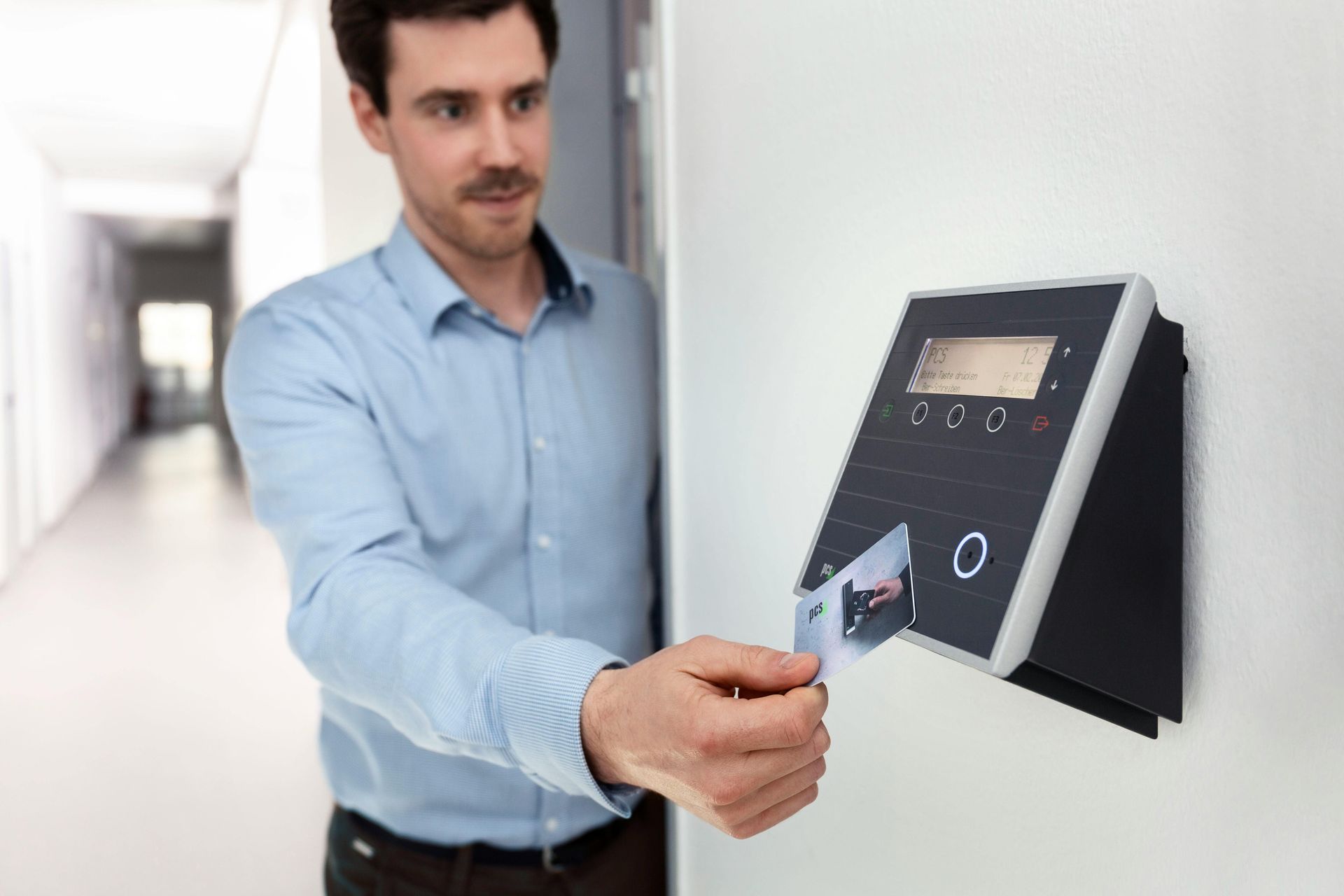 A man is using a facial recognition system to unlock a door.