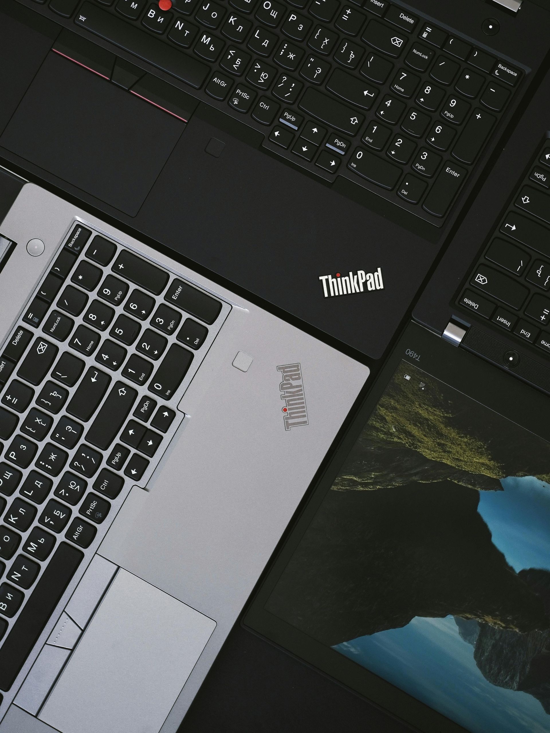 A thinkpad laptop is laying on top of another laptop