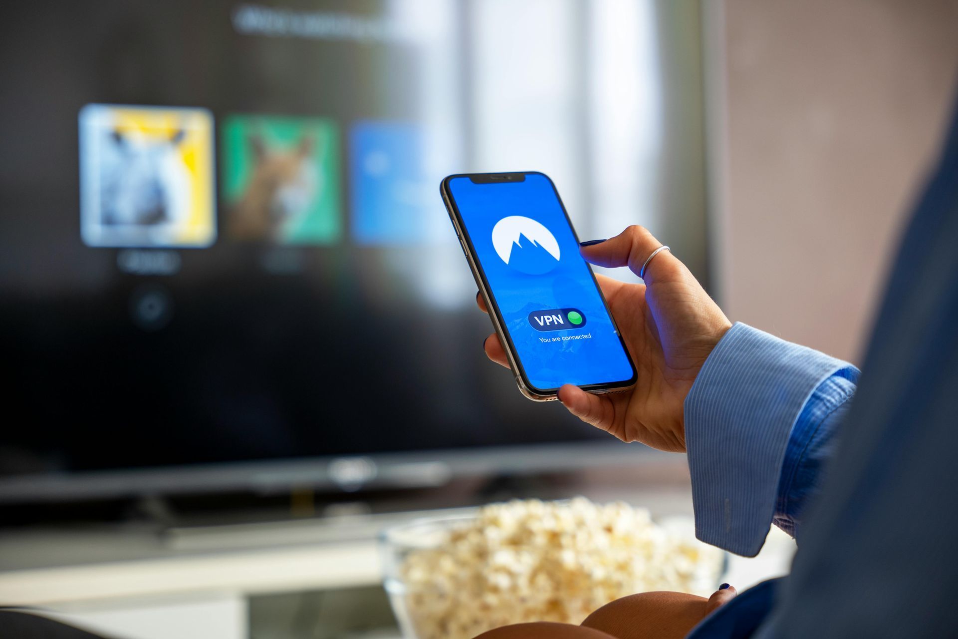 A person is holding a cell phone in front of a television.