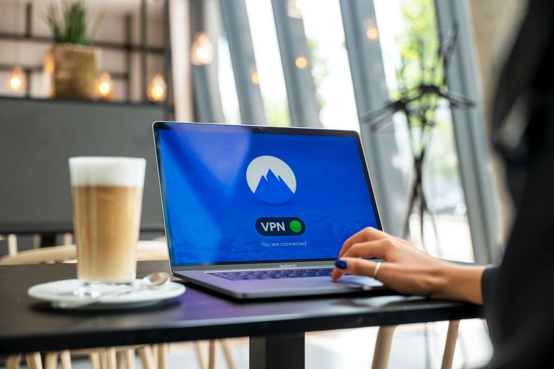 A person is sitting at a table using a laptop computer.