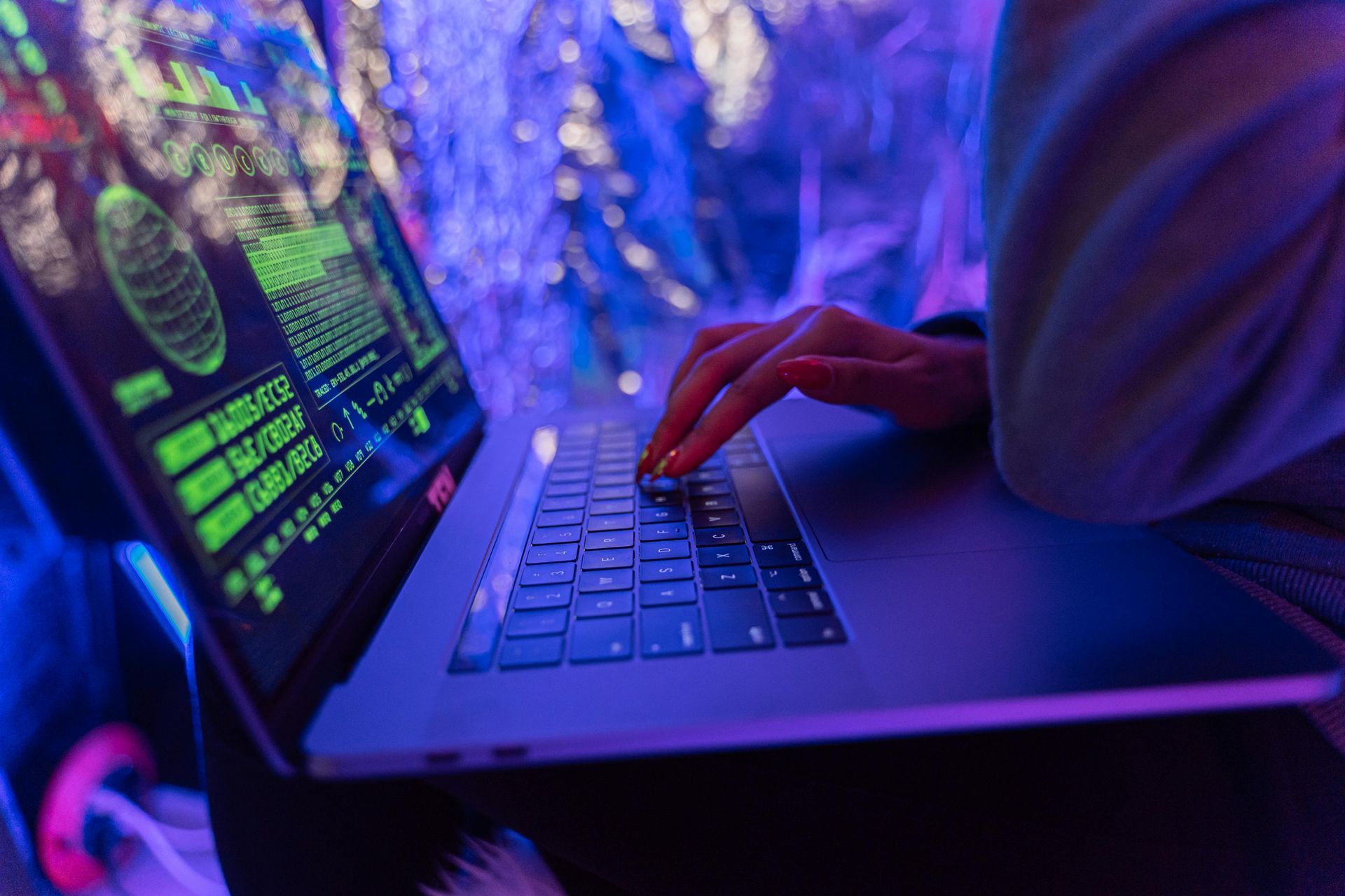 A person is typing on a laptop computer in a dark room.