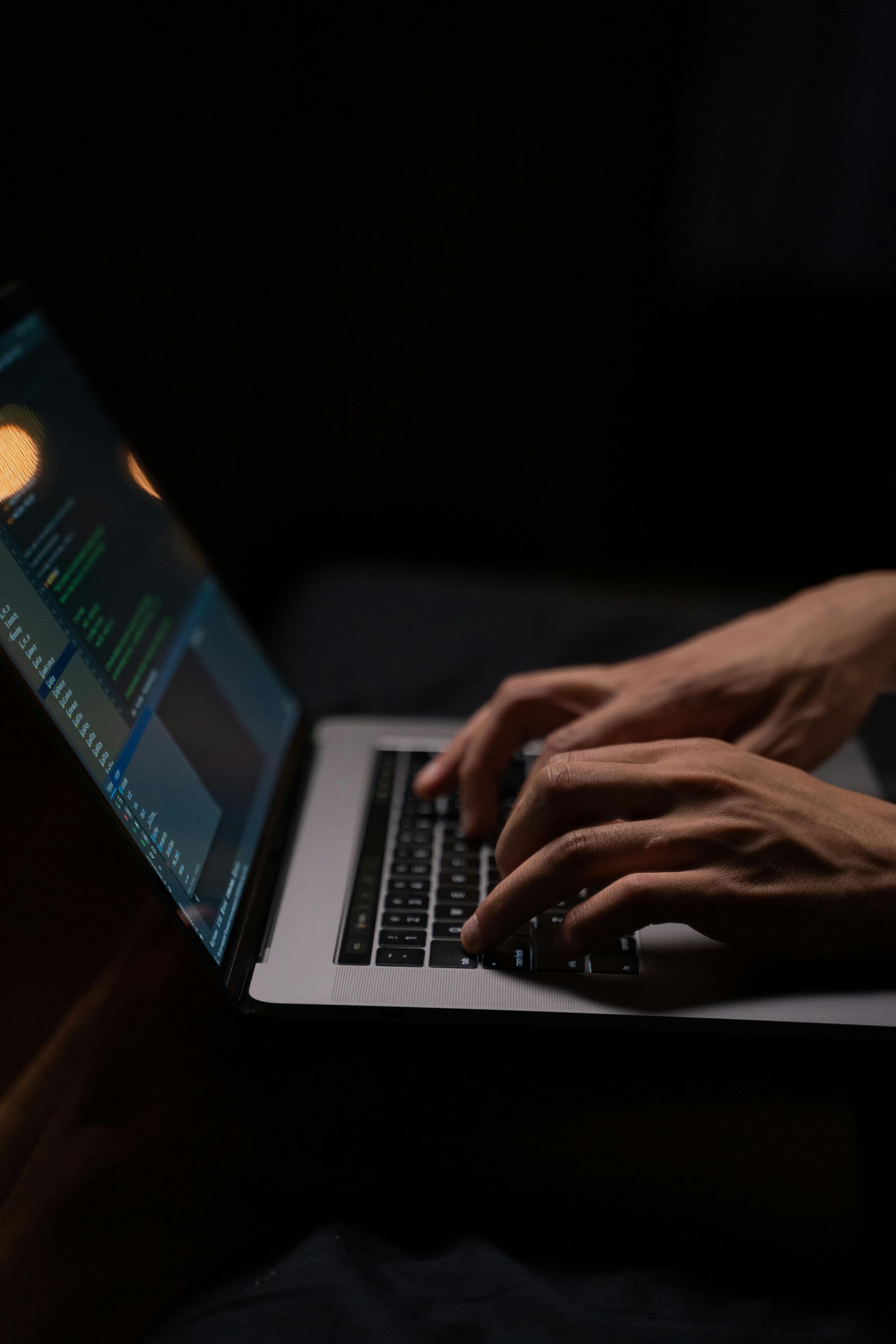 A person is typing on a laptop computer in the dark.