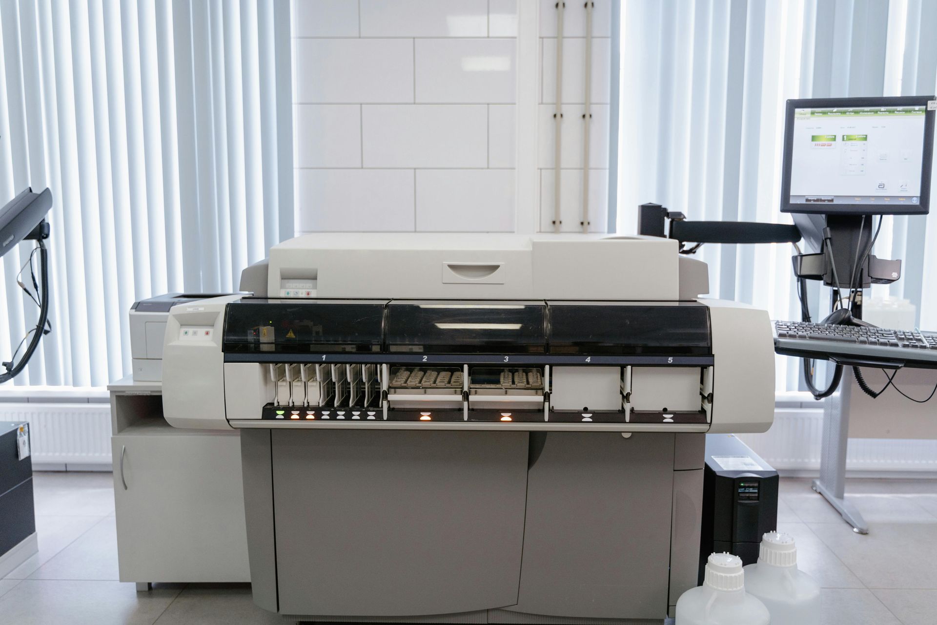 A large machine is sitting in a lab next to a computer.