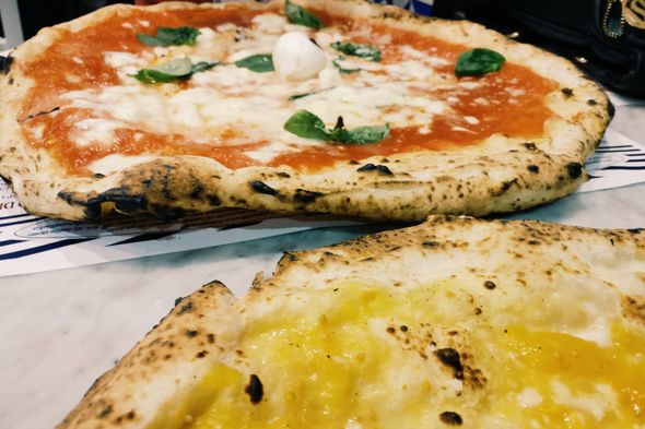 Due pizze su un tavolo, una margherita al basilico e una pizza margherita in primo piano.