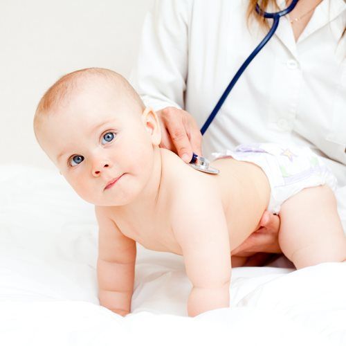 Baby being checked by a doctor with a stethoscope, lying on a white exam table