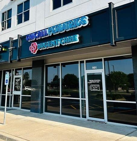 Blue storefront sign for a pediatric urgent care clinic with glass doors and windows