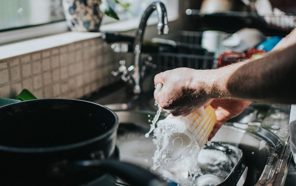 a person is washing dishes in a kitchen sink