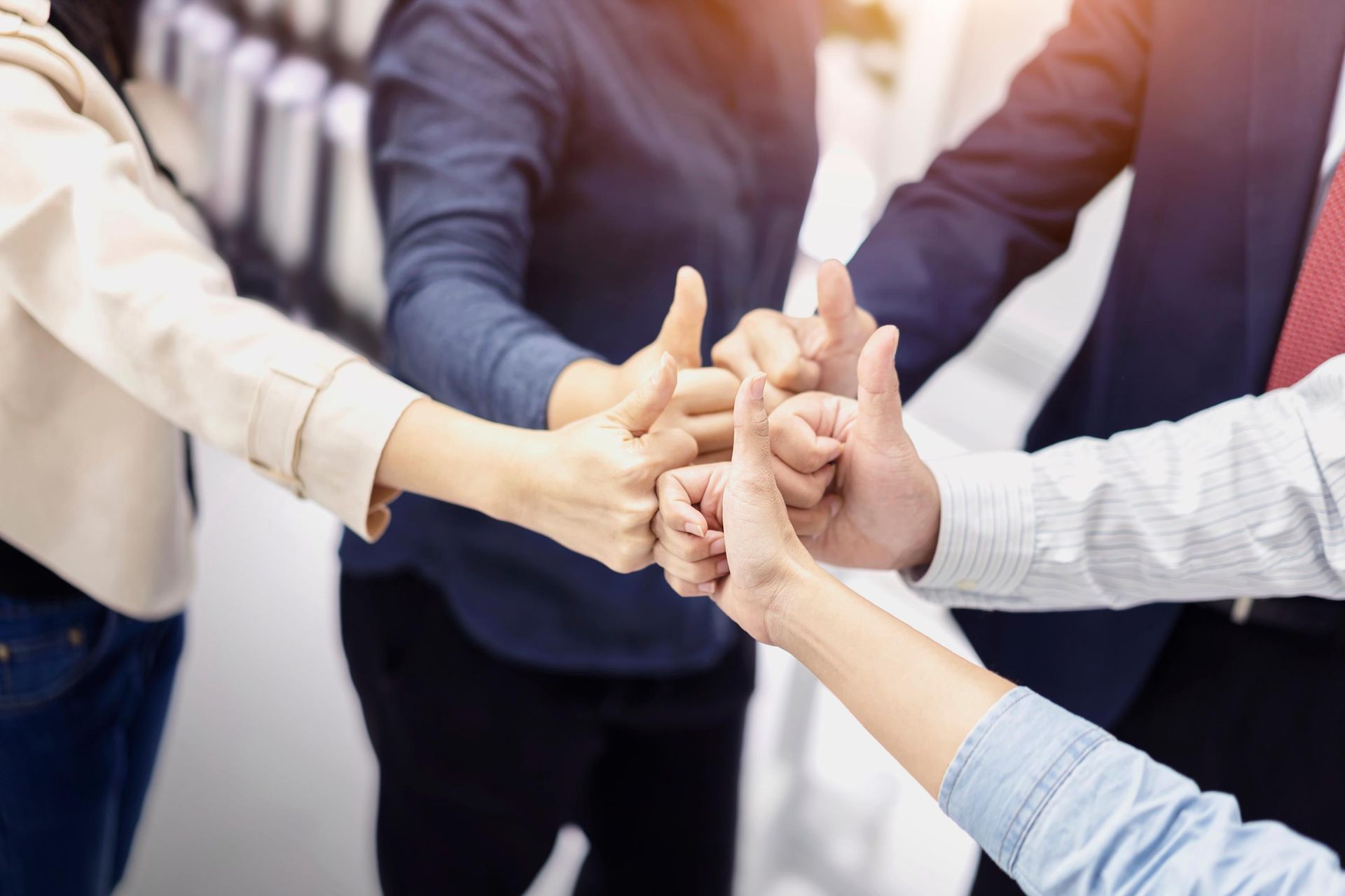a group of people putting their hands together and giving a thumbs up