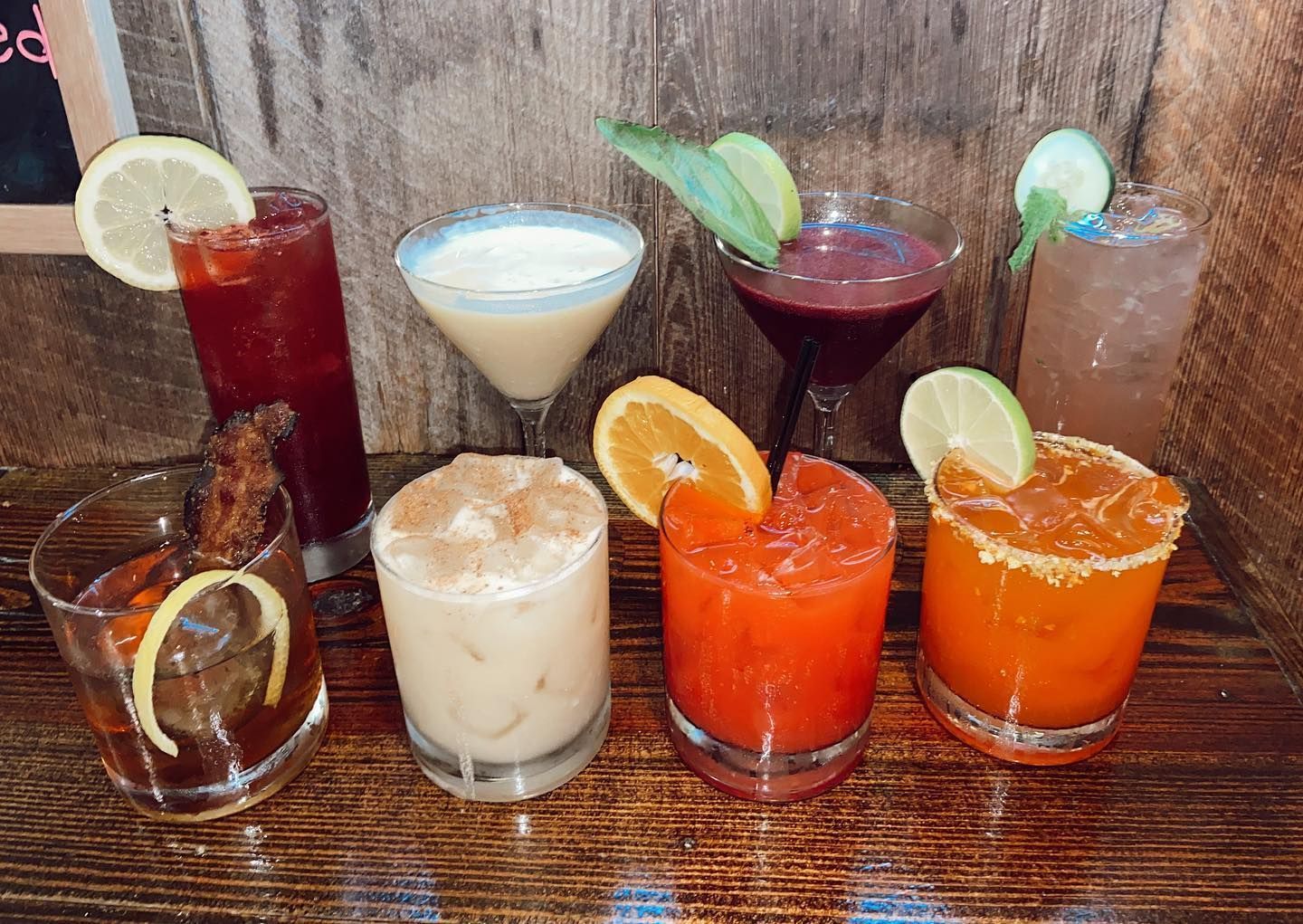 Two glasses of orange and white drinks with mint leaves on a bar.