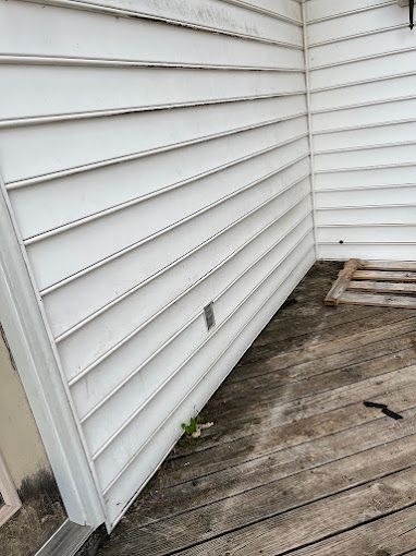 A white siding on the side of a house next to a wooden deck.
