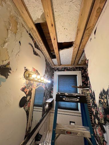 A ladder is sitting in a room with a hole in the ceiling.