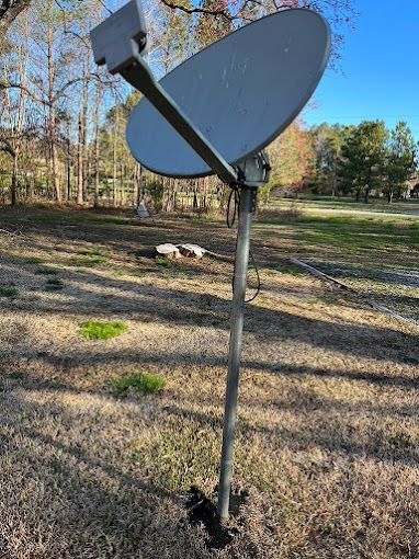 A satellite dish is sitting in the middle of a field.