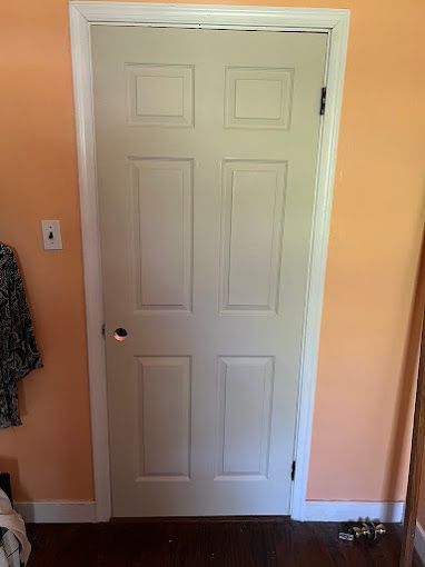 A white door is in a room with orange walls.