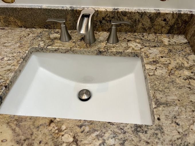 A bathroom sink is sitting on top of a granite counter top.