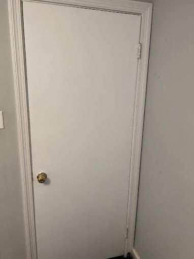 A white door with a gold knob is sitting in a corner of a room.