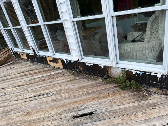 A wooden deck in front of a house with a lot of windows.