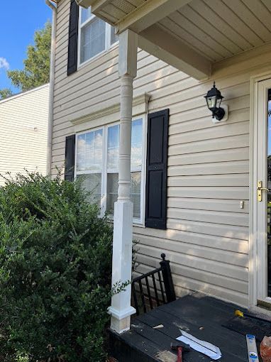 A house with a porch and a white pole in front of it.