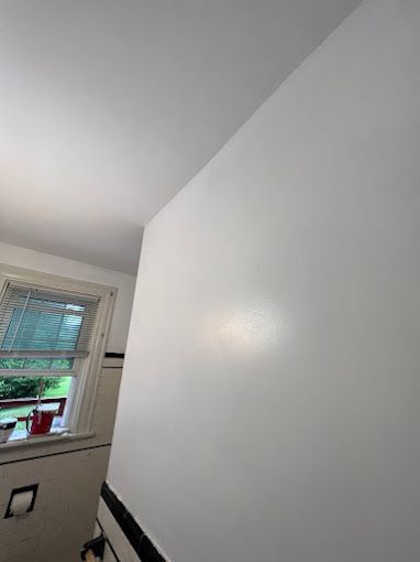 A bathroom with a white wall and a window.