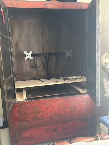 A red cabinet with a tv mounted on top of it.