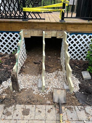 A shovel is sitting in the dirt next to a wooden deck.