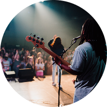 Musician playing bass onstage before a cheering crowd under spotlights