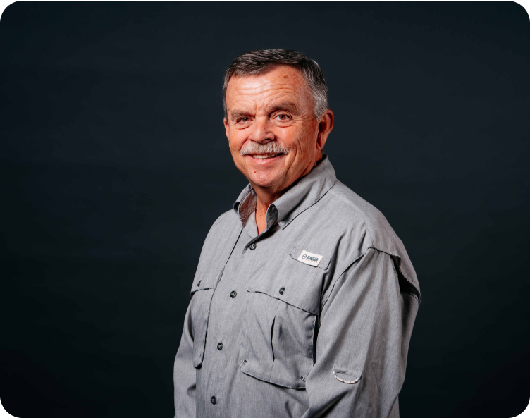 Smiling man in a gray shirt against a dark studio background