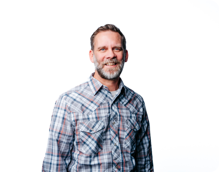 Smiling man in a plaid shirt standing against a white background