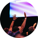 Audience raising hands at a concert under purple stage lights