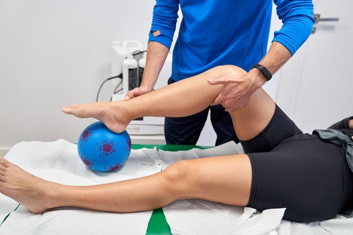 Man in black shirt on exercise ball assisted by therapist, stretching arms in clinic. Man in black shirt on exercise ball assisted by therapist, stretching arms in clinic.