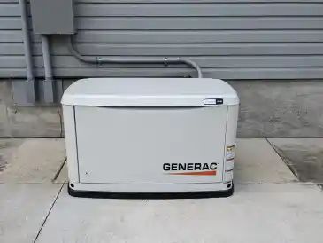 White Generac home standby generator beside a house on a concrete pad