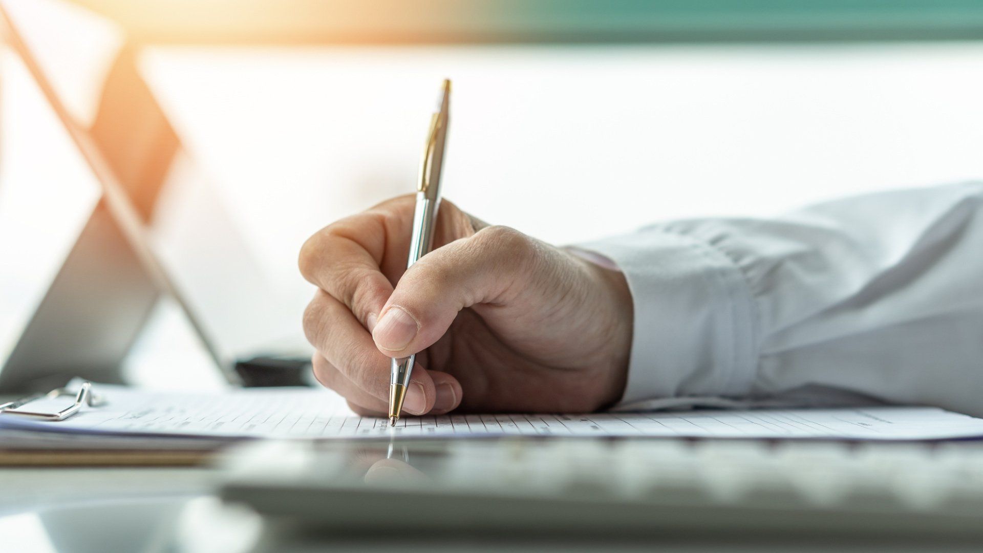 A person is writing on a piece of paper with a pen.
