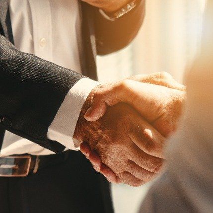 A man in a suit and tie shakes hands with another man