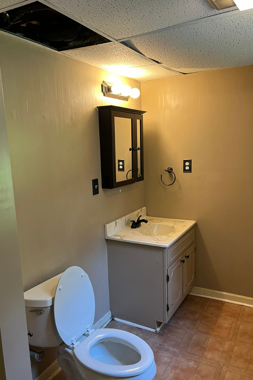 A bathroom with a toilet , sink and mirror.