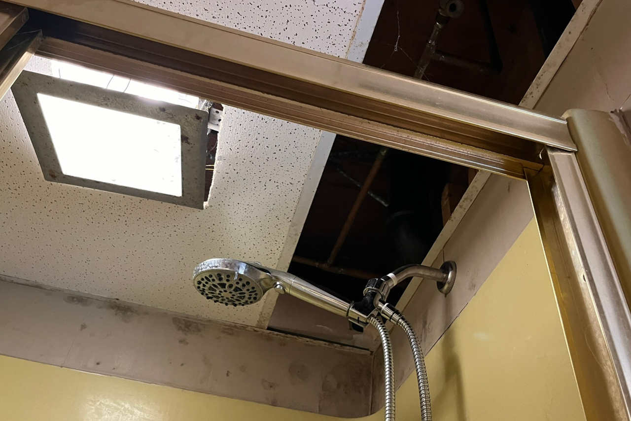 A shower head is hanging from the ceiling in a bathroom.