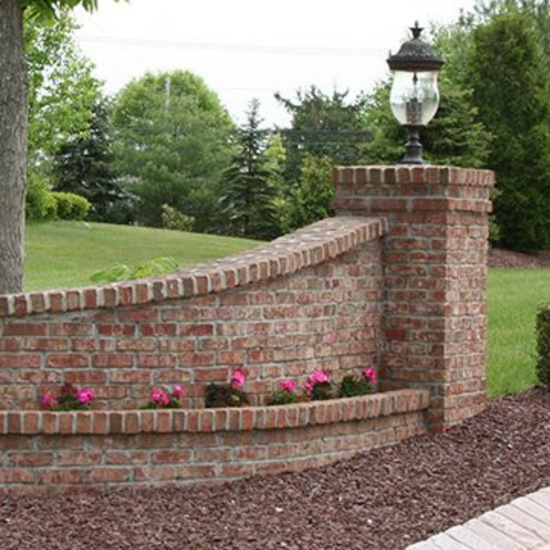 A brick wall with flowers and a lamp on top of it