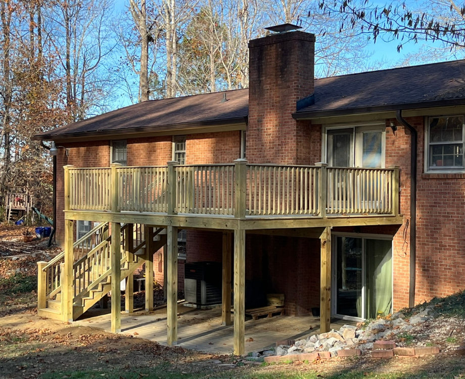 A brick house with a wooden deck and stairs.