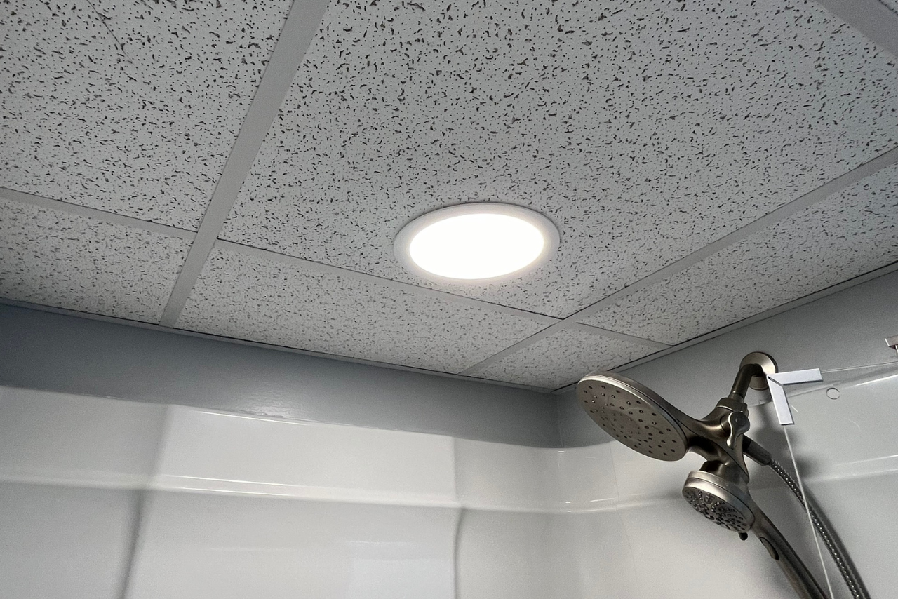 A shower head is hanging from the ceiling of a bathroom.